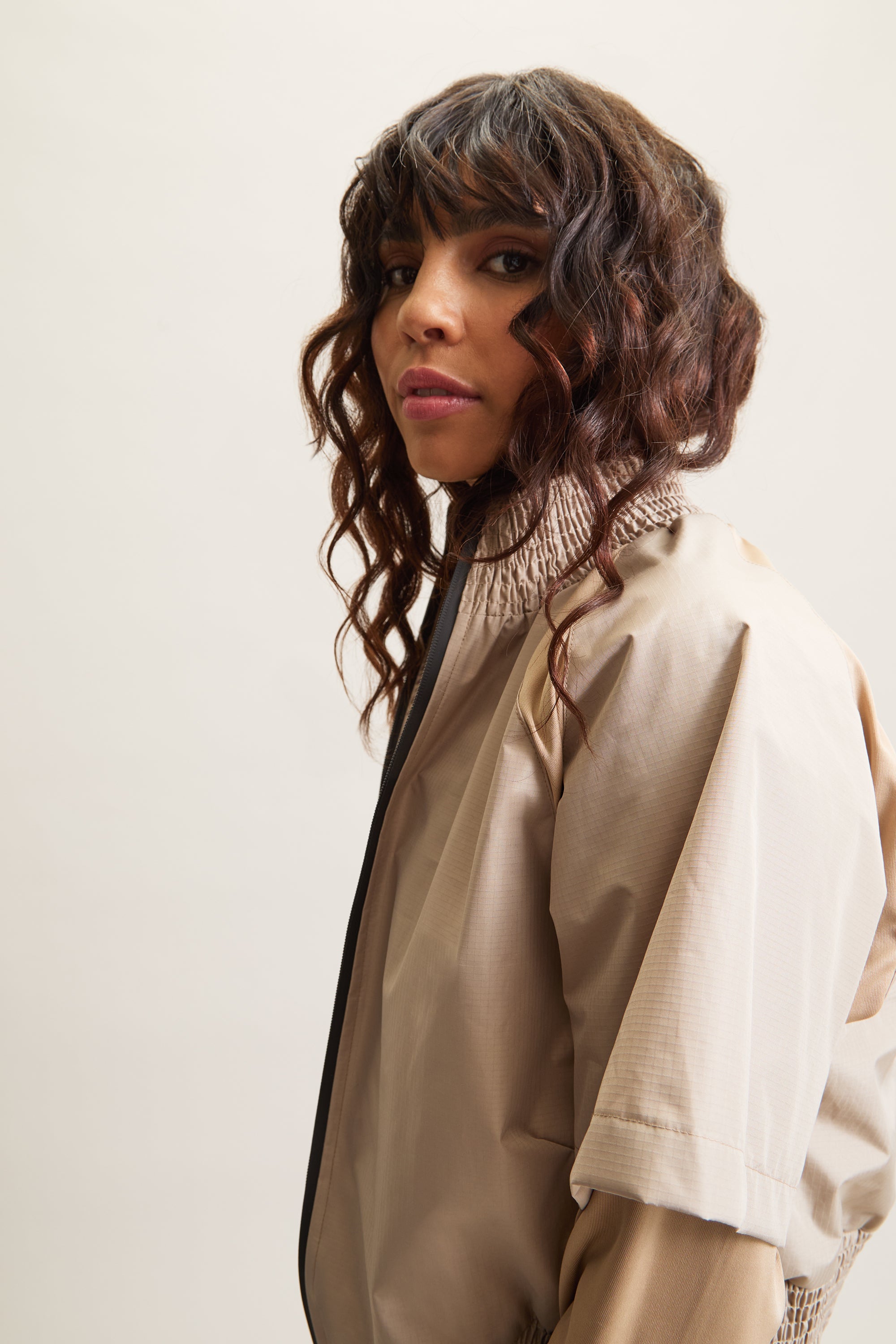 Women's HRMN8 beige, cream, brown Pace Jacket with buttery-soft sleeves, lightweight nylon shell, and elasticated waist for a flattering fit. Designed for movement, this versatile zip-up jacket is ideal for activewear, athleisure, and post-workout layering. Pairs effortlessly with Stride Flare Pants for a sporty, gym-ready look or with Persuasion Linen Pants for a contemporary, everyday outfit. A must-have for modern street style, travel, and transitional seasonal wear.