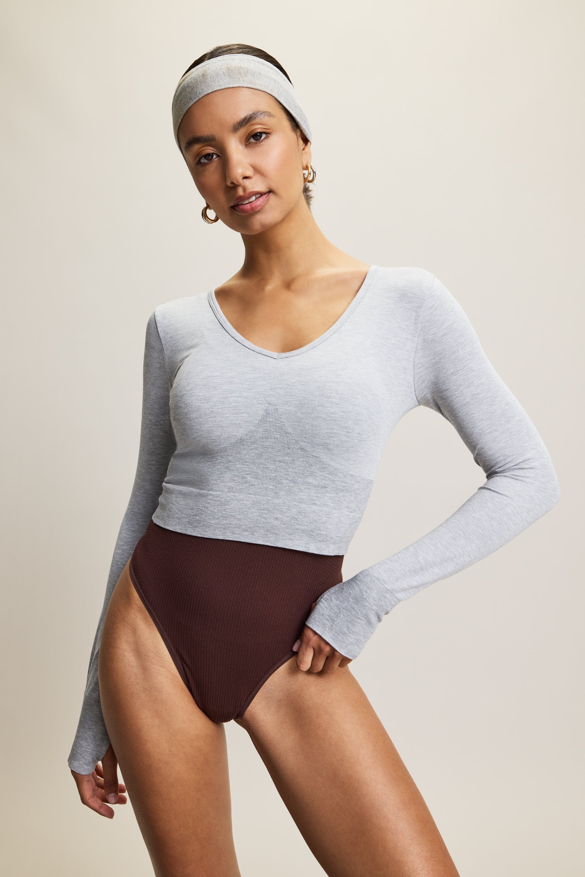Grey stylish cropped long-sleeve athleisure top made from eco-friendly bamboo fabric, featuring a flattering V-neckline, thumbholes for added comfort, and contouring panels for a sculpted fit. Perfect for activewear, this moisture-wicking and breathable top is ideal for workouts, yoga, and casual everyday outfits.
