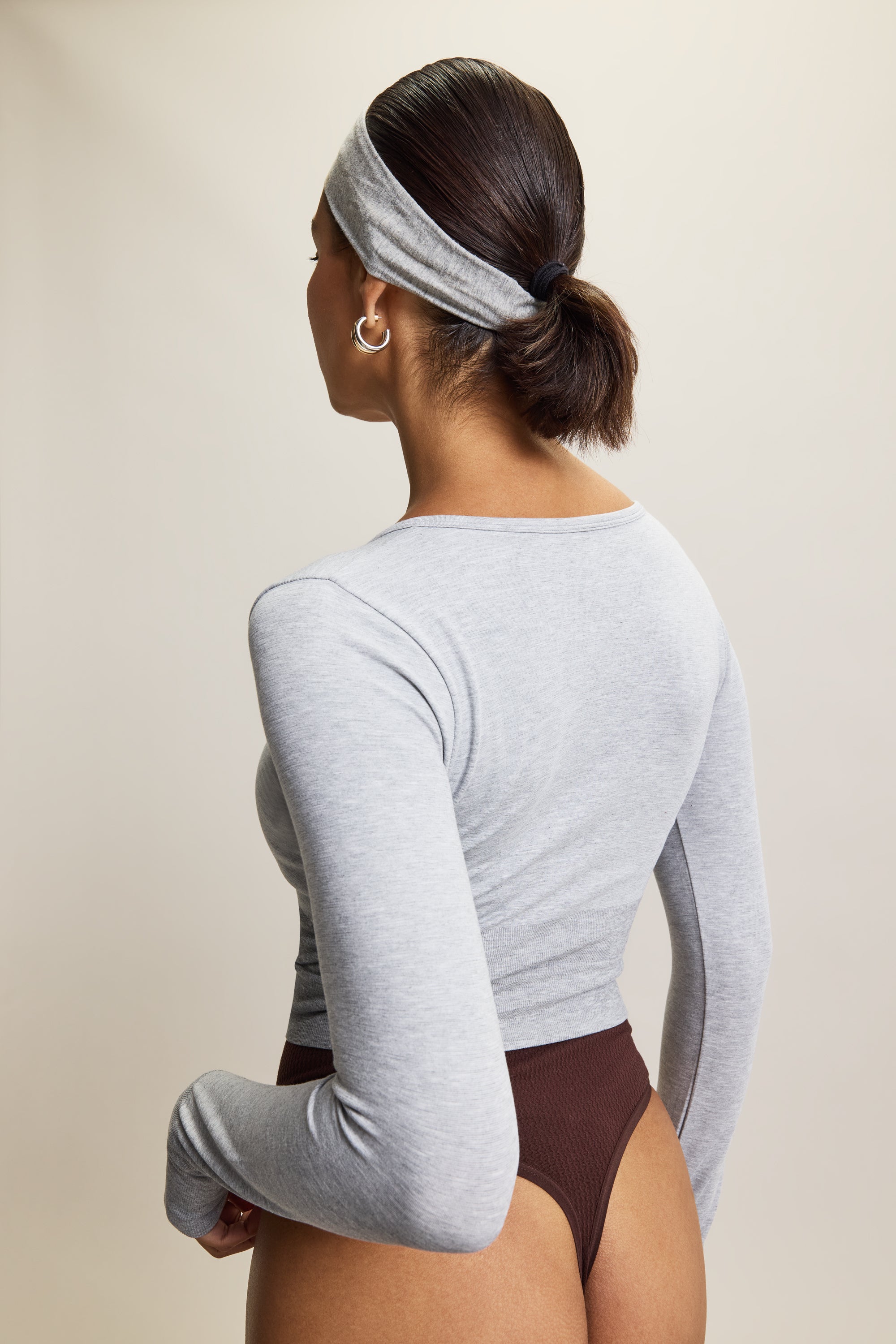 Grey stylish cropped long-sleeve athleisure top made from eco-friendly bamboo fabric, featuring a flattering V-neckline, thumbholes for added comfort, and contouring panels for a sculpted fit. Perfect for activewear, this moisture-wicking and breathable top is ideal for workouts, yoga, and casual everyday outfits.